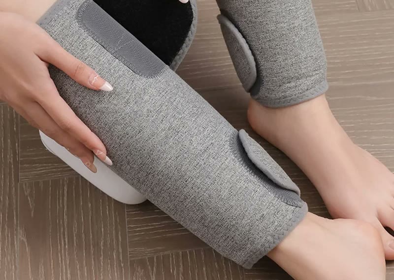 Hands adjusting the overlapping fabric wrap around a calf before securing the closure.